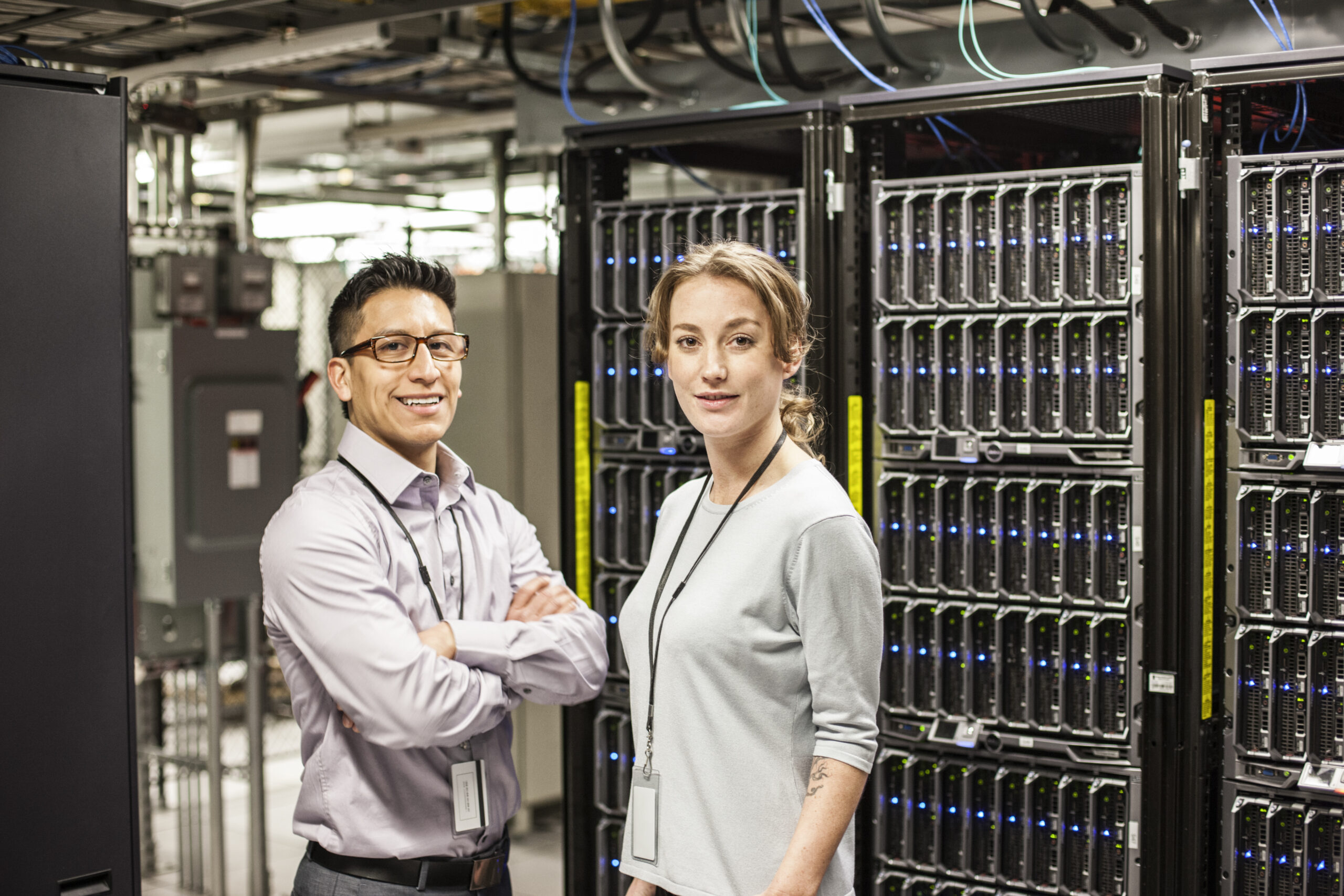 Caucasian man and woman technicians in a large computer server farm.
