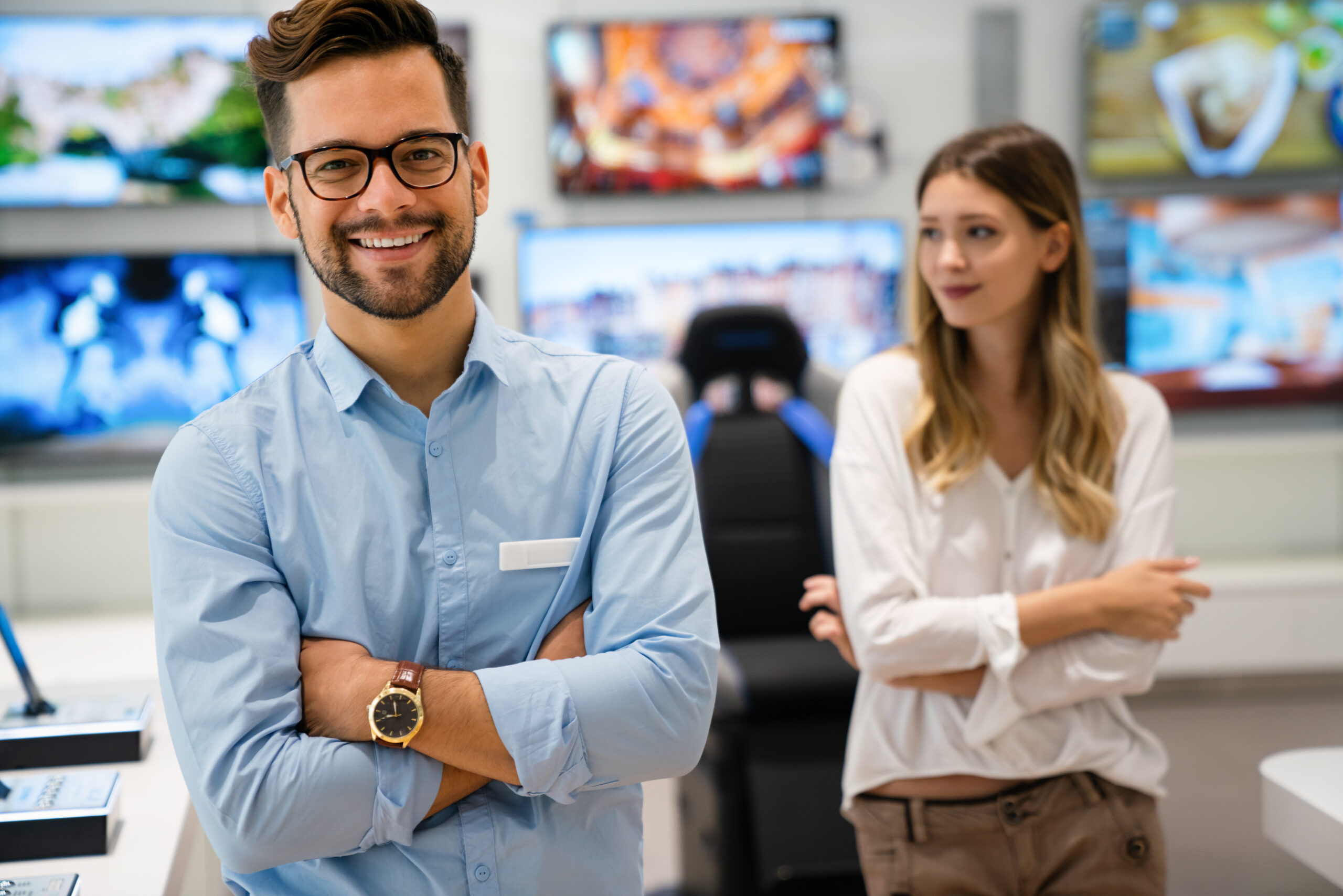 Happy seller man helping to woman to buy a new digital smart device in tech store. Technology people concept