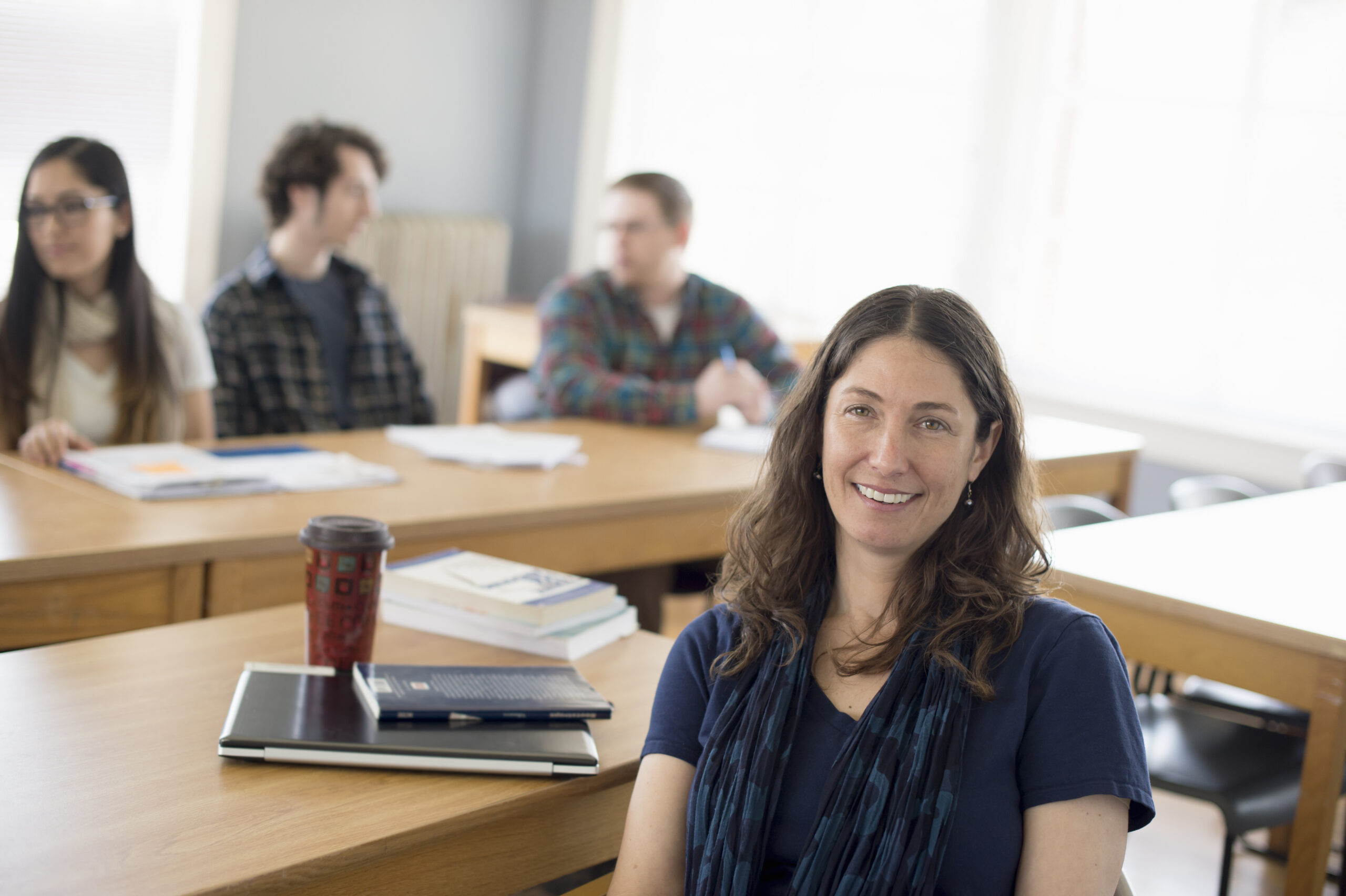 Teacher sitting at desk, portrait